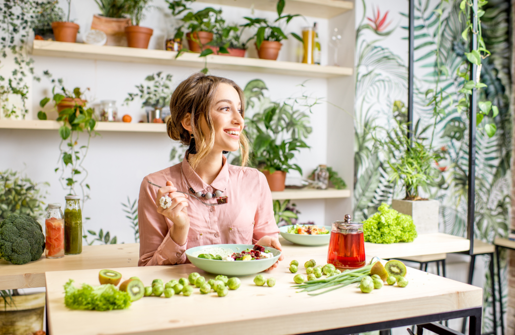 femme dans une cuisine qui mange des légumes verts